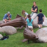 Family playing around rocks and dolphin sculptures Opens in new window