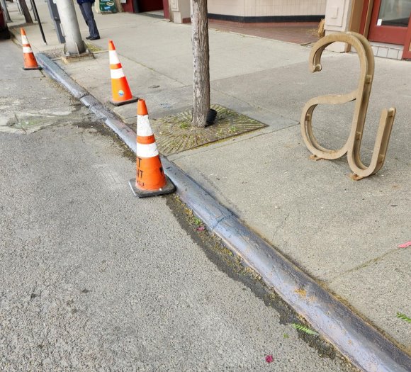 Grey curb with orange cones saying 'Wet Paint' 