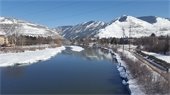 Picture of the Clark Fork River with snow on the ground, on the river bank, and on Mount Sentinel behind the river.