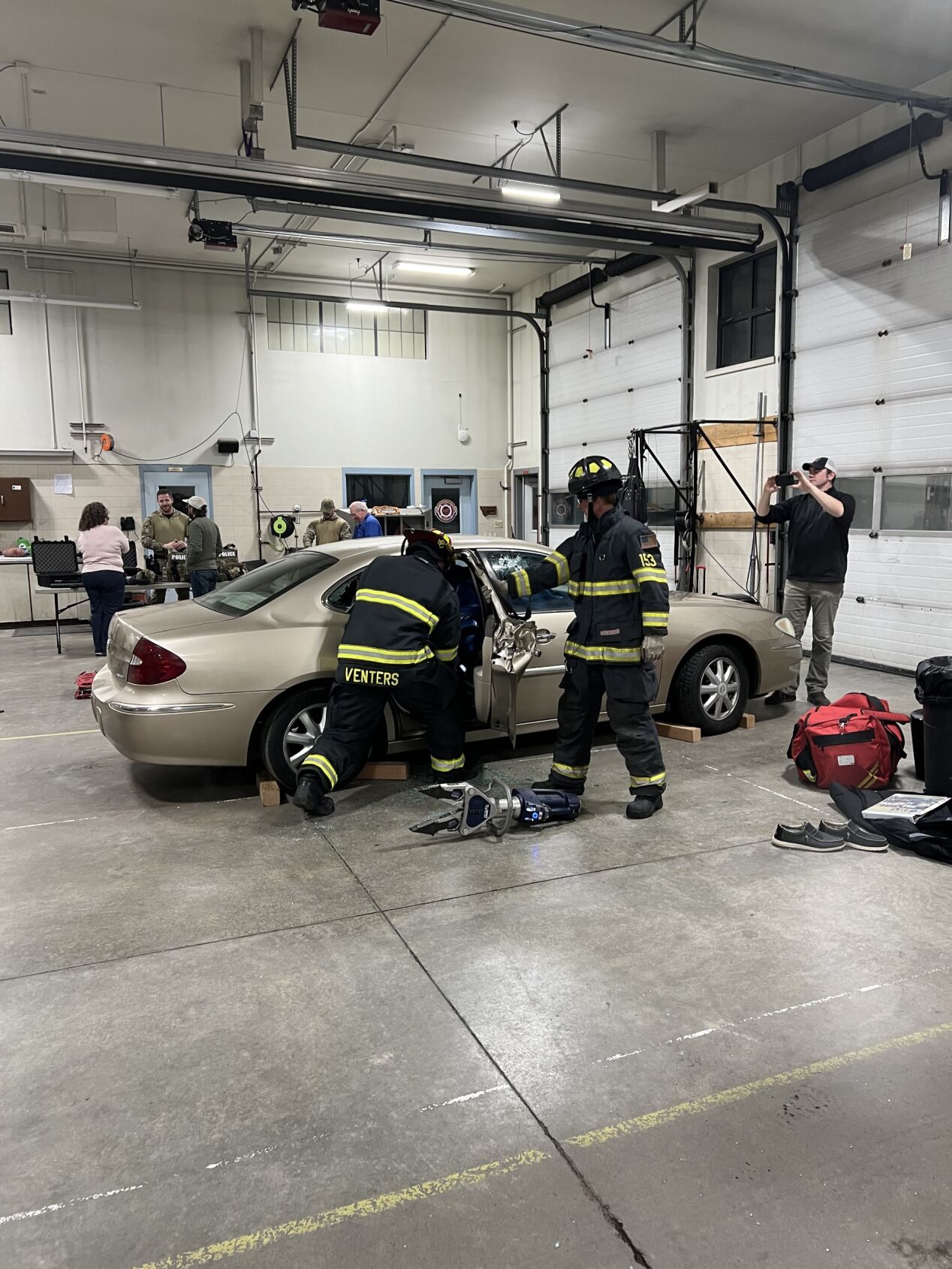 Firemen demonstrating the jaws of life on car in the firestation 
